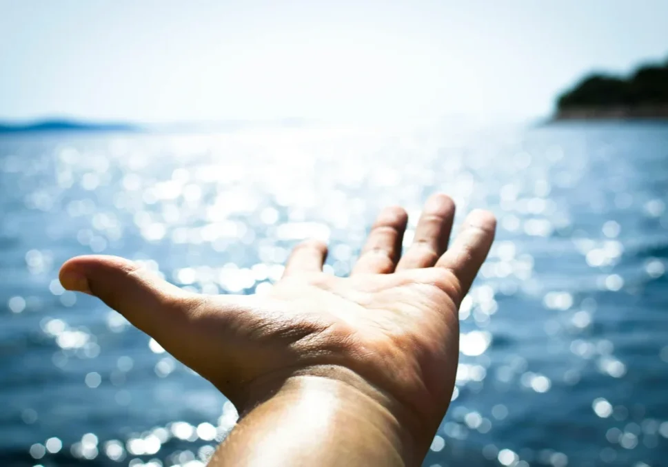 A hand reaching out of the water to catch something.